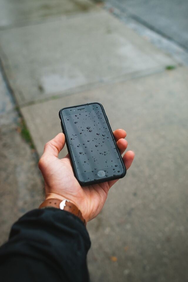 a hand holding a wet iphone