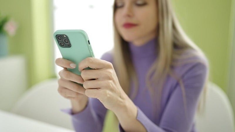 blonde woman using iphone while sitting