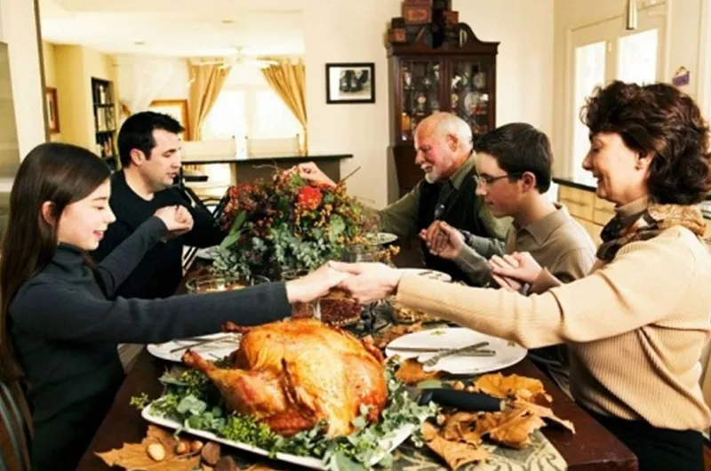 Family praying together before thanksgiving feast