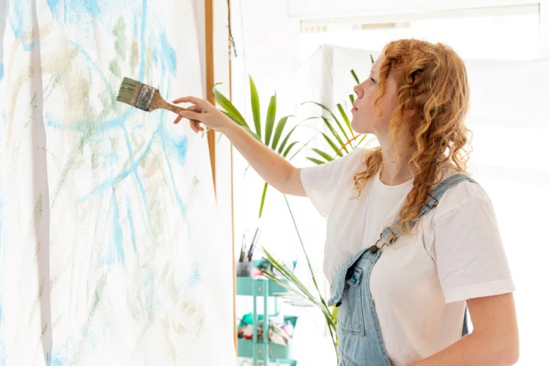 a woman brushing paint on canvas