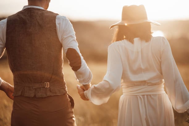 Newlyweds walking hand in hand at sunset with the Golden Hour filter applied for warm tones.
