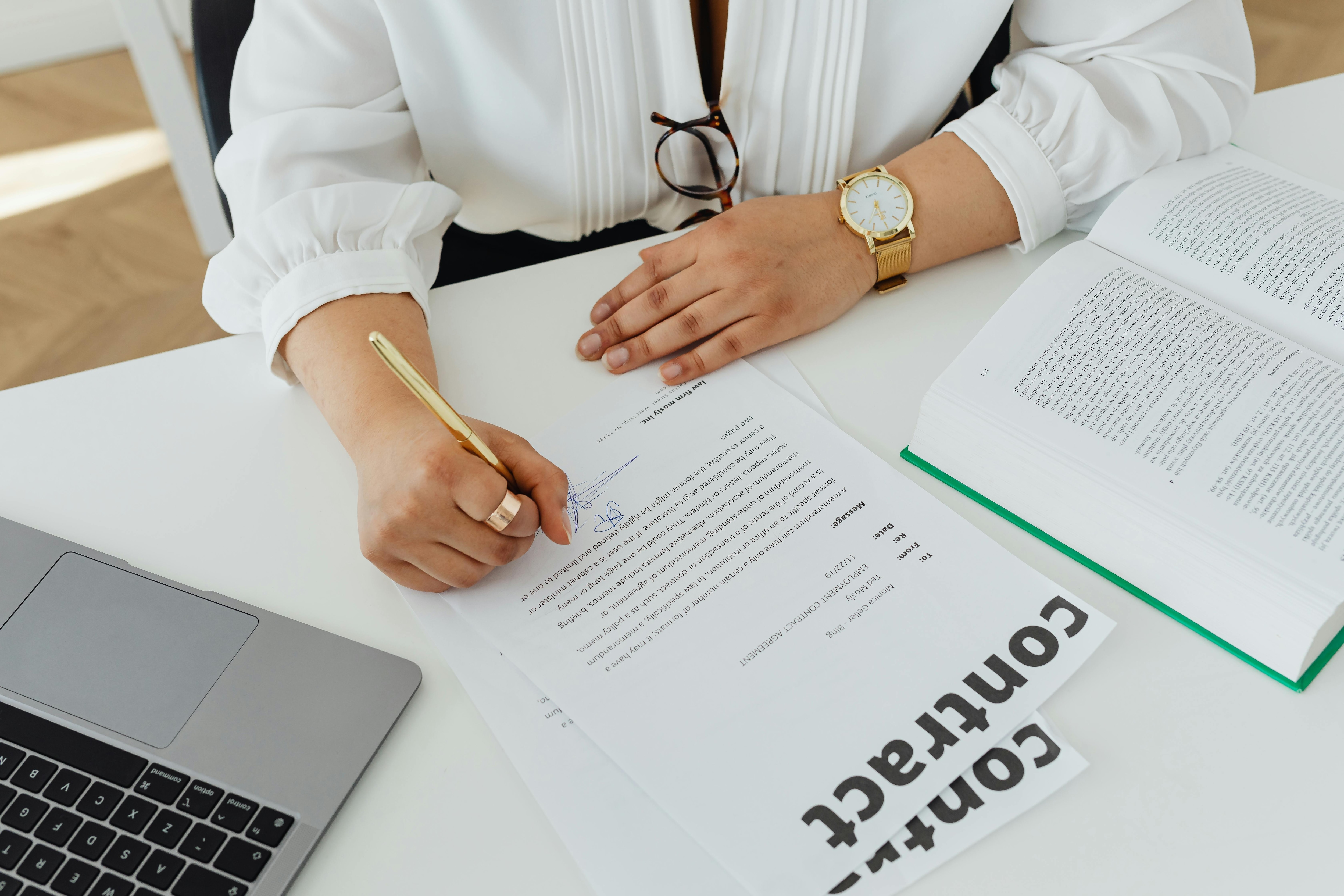 Businesswoman signing a contract beside a laptop in a paperless office workflow