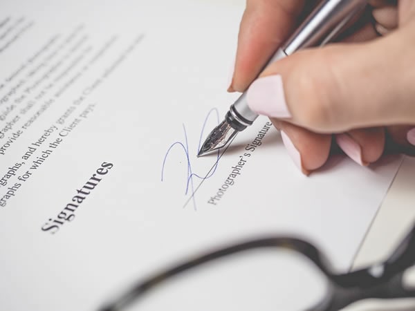 una persona firmando un documento impreso