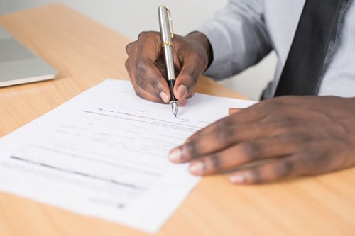 homme signant un document imprimé