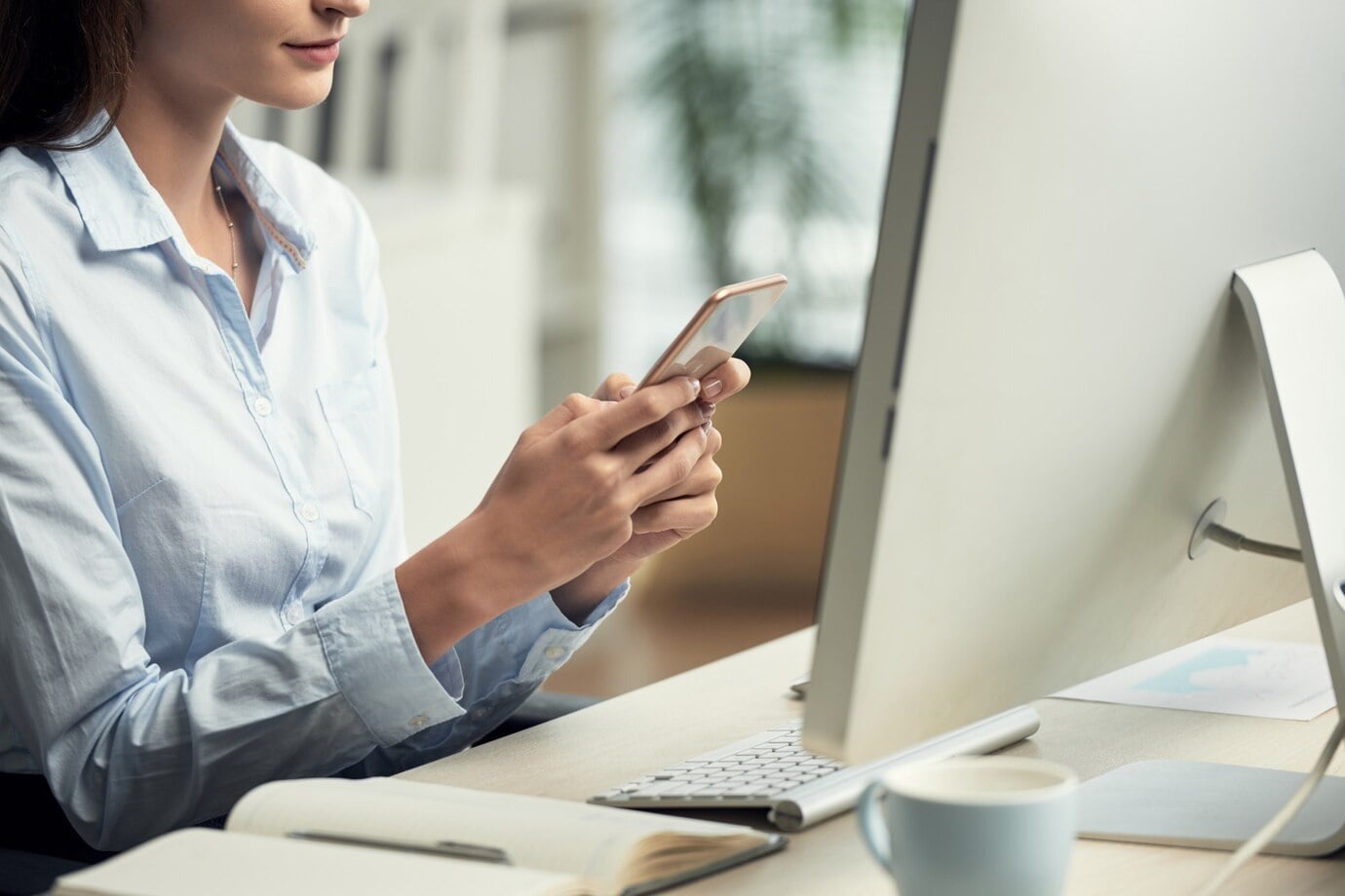 woman sitting in office using iphone