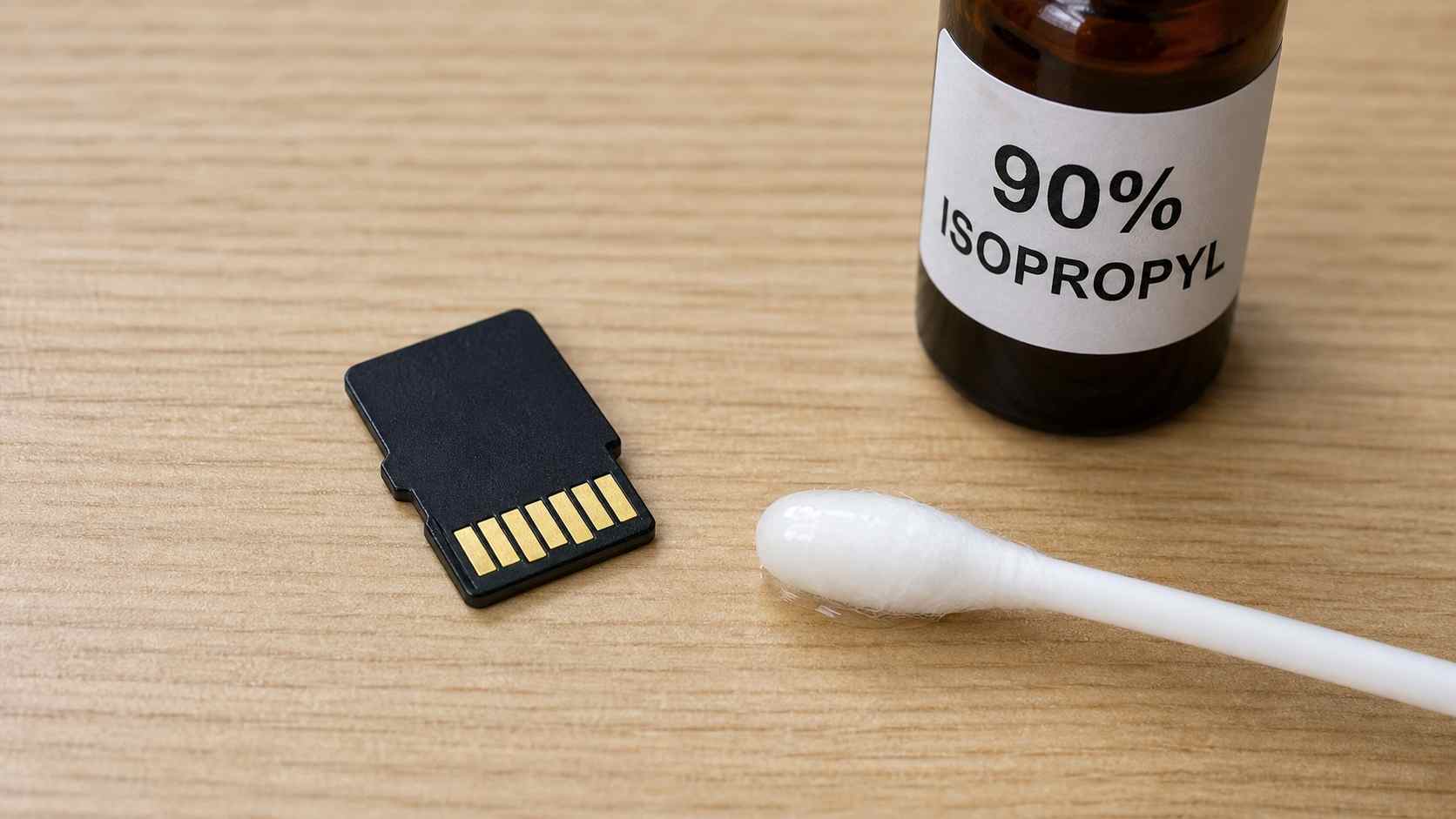 microsd card gold contact pins being cleaned with a cotton swab dipped in 90 percent isopropyl alcohol