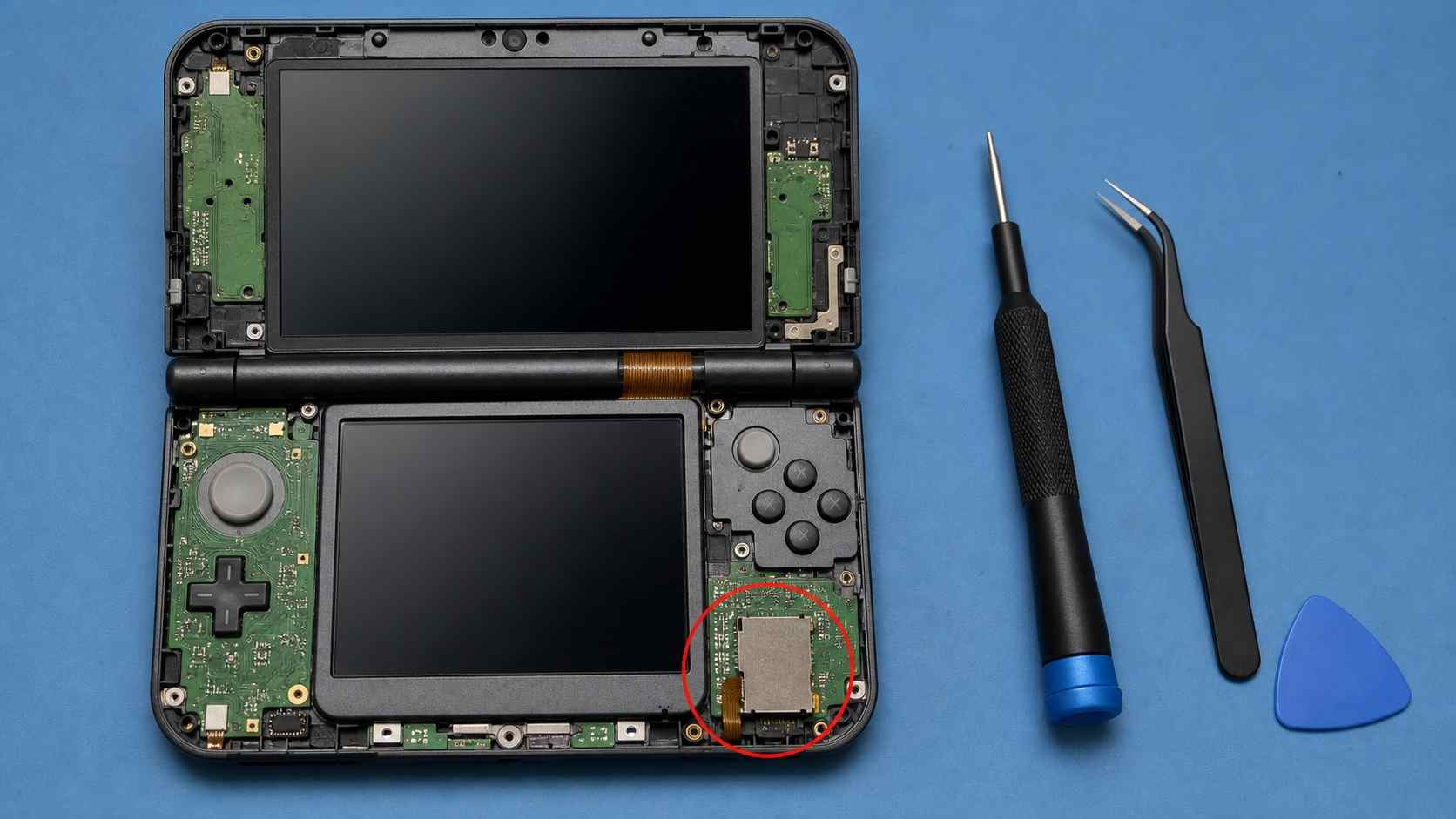 disassembled dual-screen handheld console on a technician mat with the sd card reader ribbon module highlighted for replacement