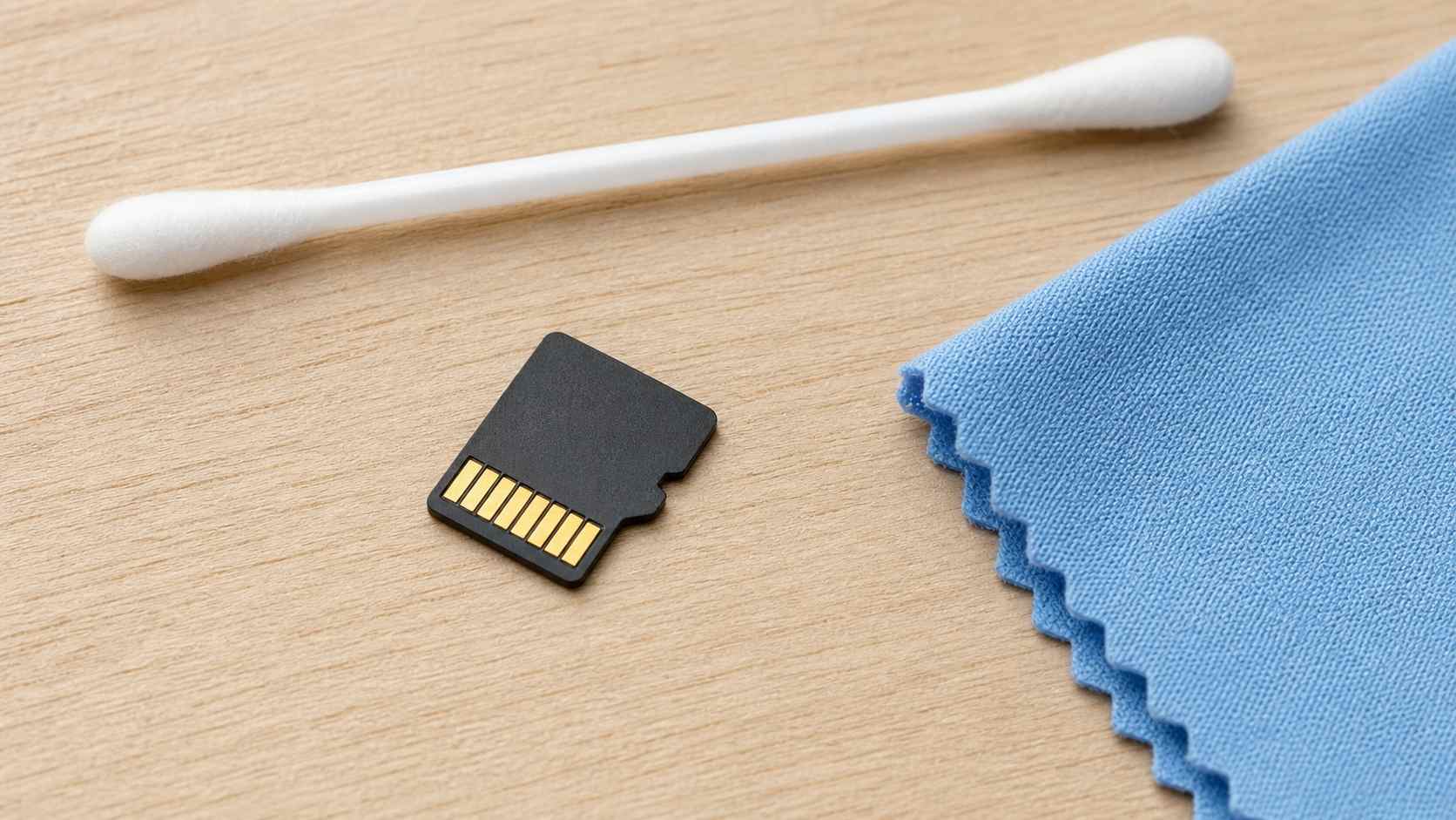 microsd card gold contact pins being cleaned with a dry cotton swab and microfiber cloth