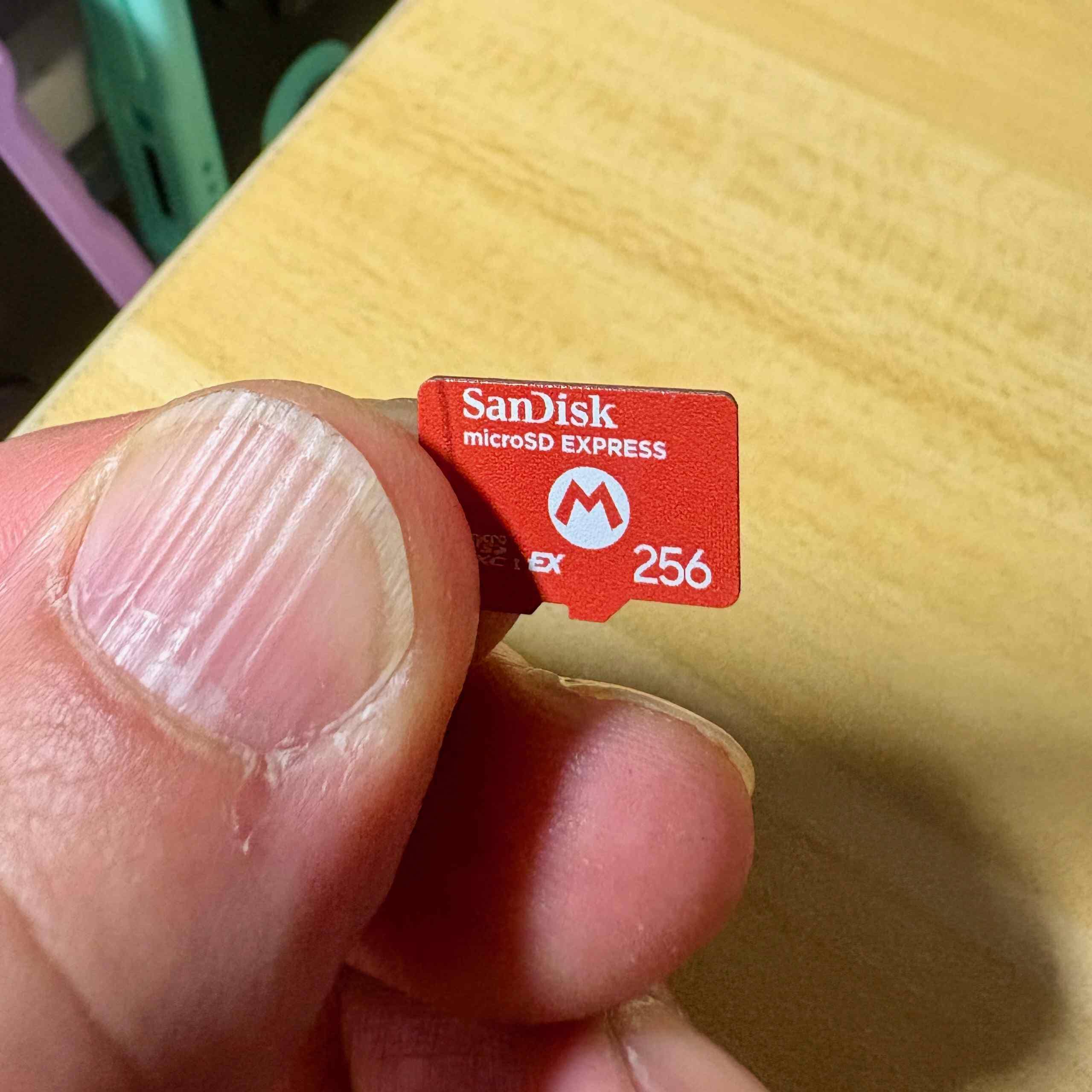 microsd card held between fingers showing storage capacity marking and brand imprint on the label side