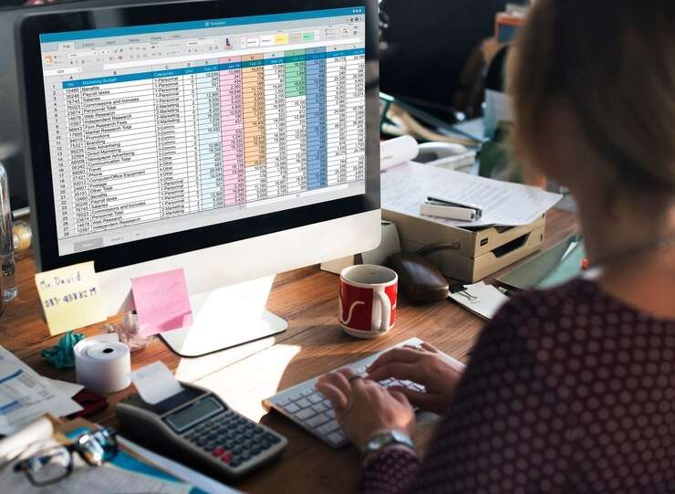 femme tapant au clavier et travaillant sur des feuilles de calcul