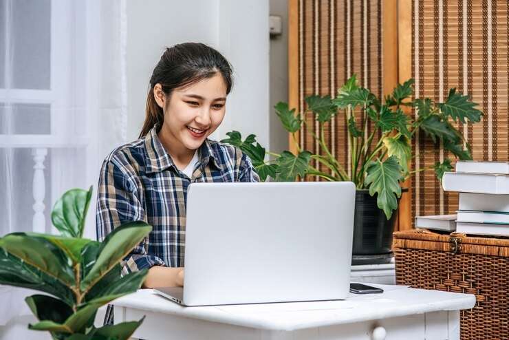 mujer sonriendo mientras utiliza el portátil