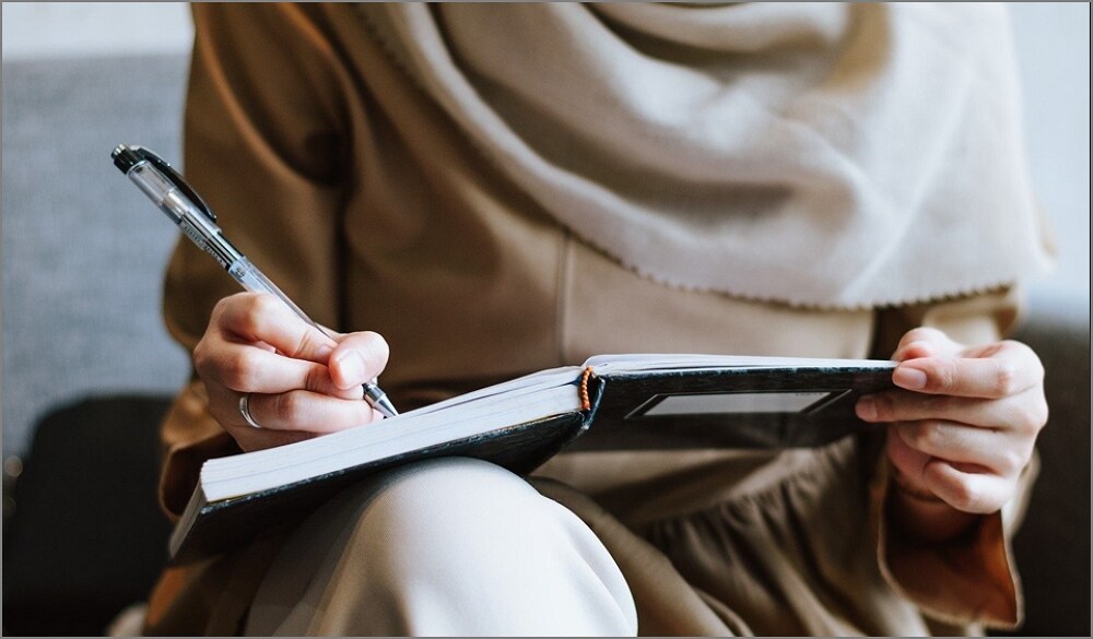 a person writing on a book.