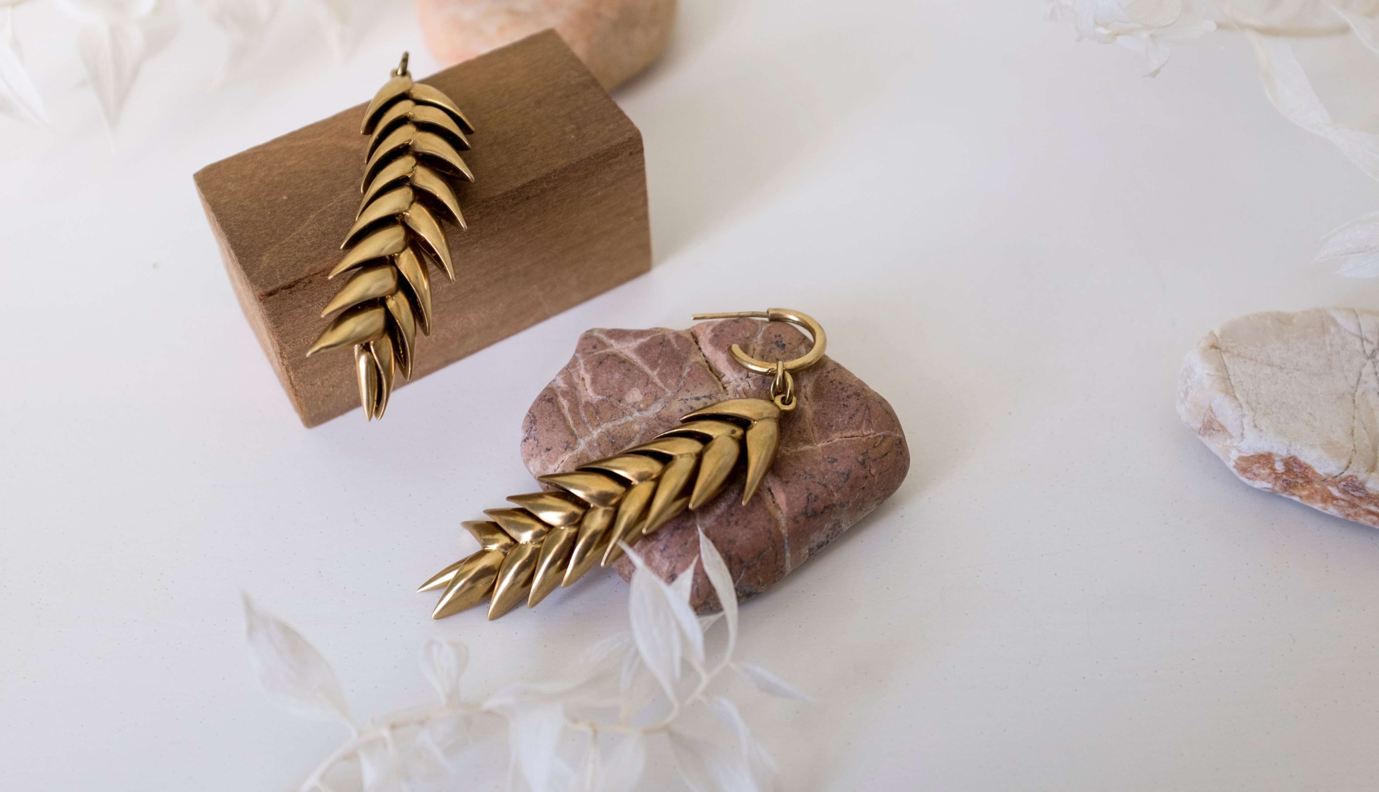 golden earrings placed over rocks and wooden blocks 