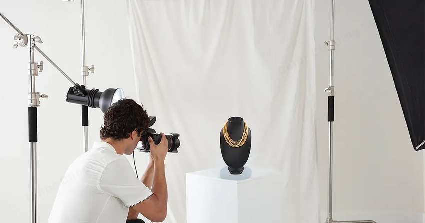 a photographer snapping photos in a gold necklace photography environment